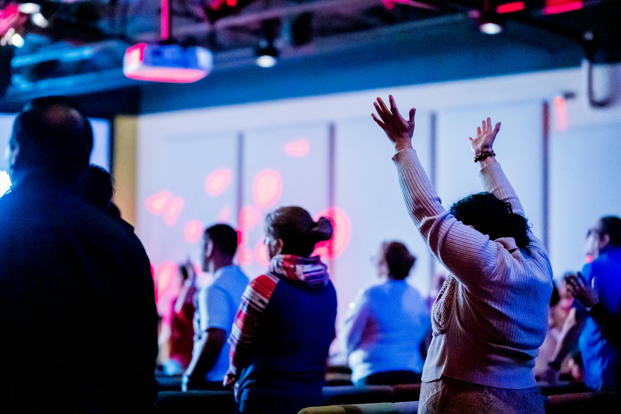 A group of people enthusiastically raising hands during a vibrant indoor event.