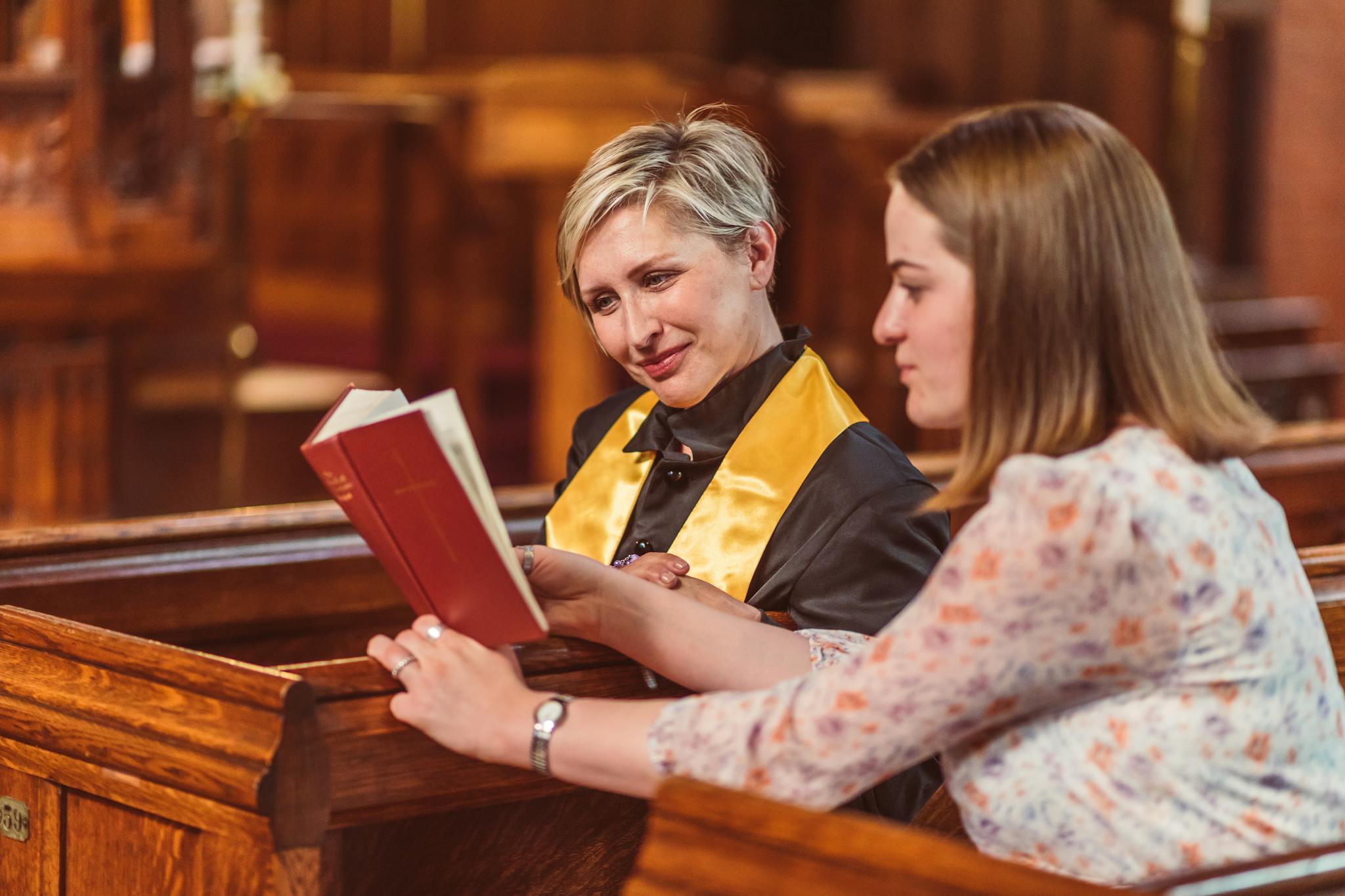 Two women in a church discussing scripture together, fostering spiritual growth and connection.